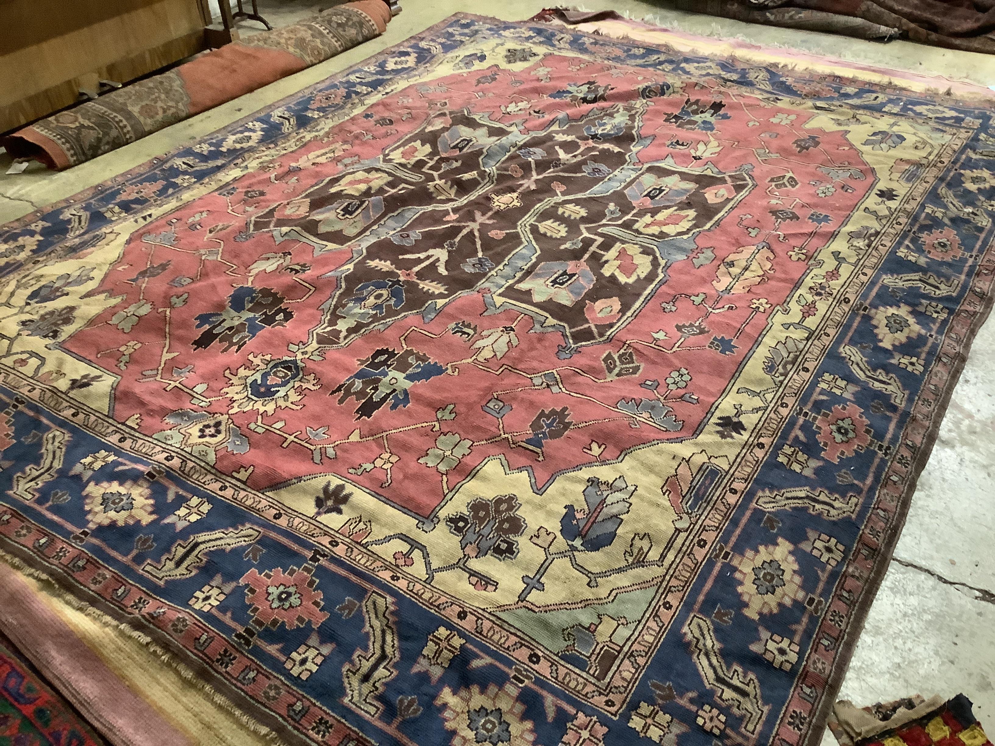 A Persian style pink ground carpet with field of foliate, motifs, multi bordered, 351 x 291cm